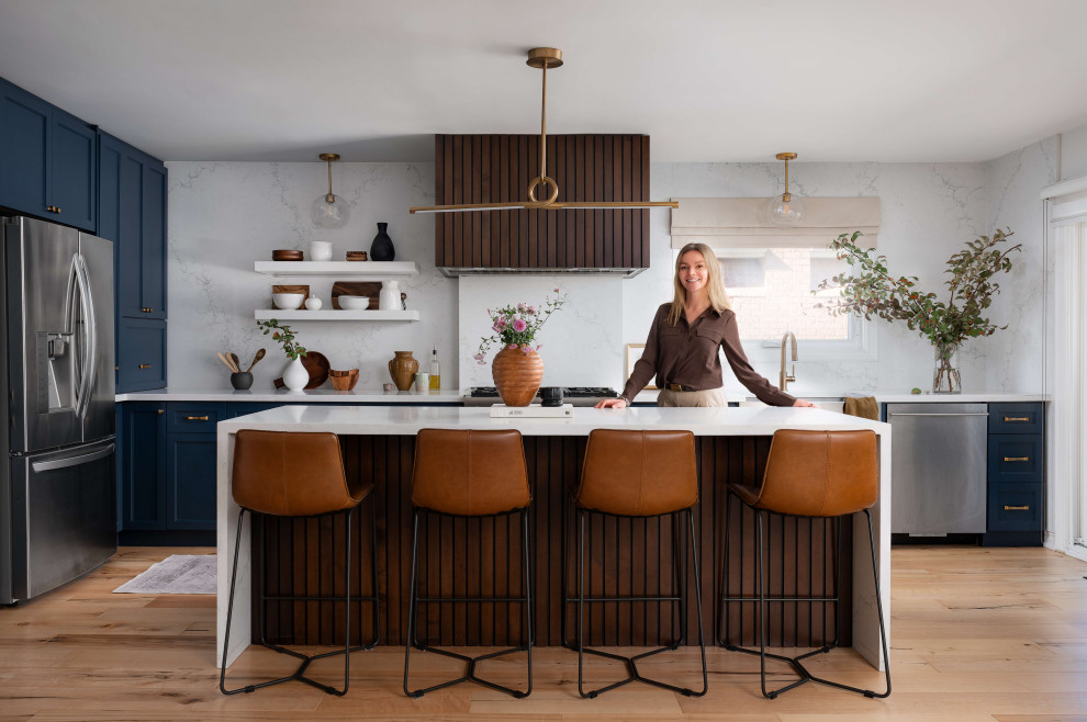 Eat-in kitchen - mid-sized transitional l-shaped medium tone wood floor and beige floor eat-in kitchen idea in Toronto with a farmhouse sink, shaker cabinets, blue cabinets, quartz countertops, white backsplash, quartz backsplash, stainless steel appliances, an island and white countertops