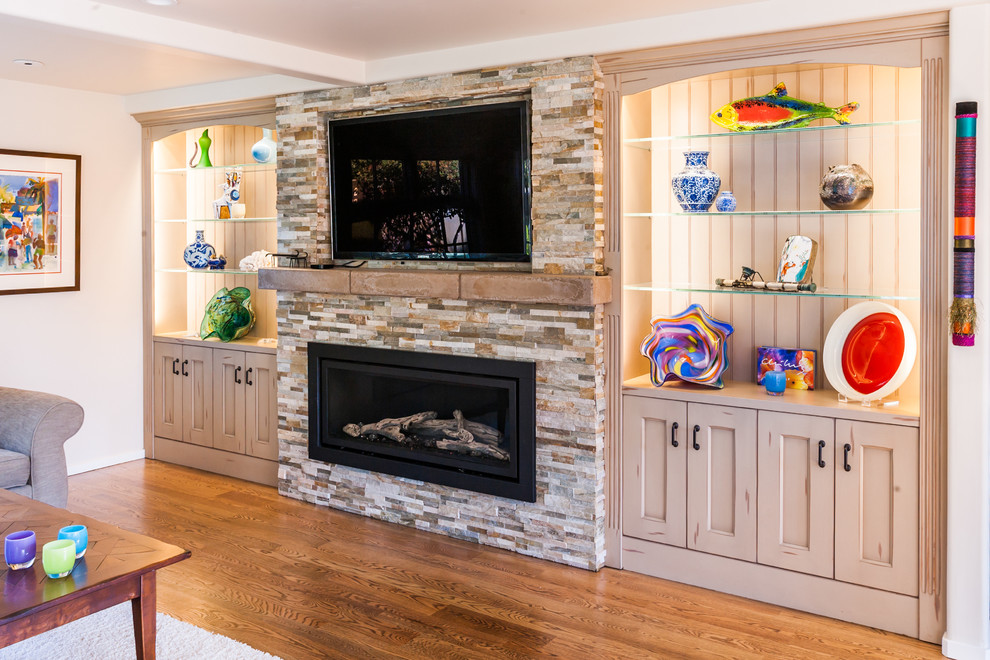 This is an example of a mid-sized beach style enclosed family room in San Francisco with beige walls, medium hardwood floors, a standard fireplace, a brick fireplace surround and a built-in media wall.