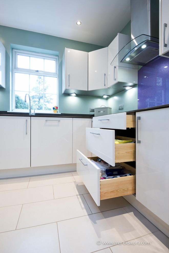 This is an example of a contemporary u-shaped eat-in kitchen in London with flat-panel cabinets, white cabinets and no island.