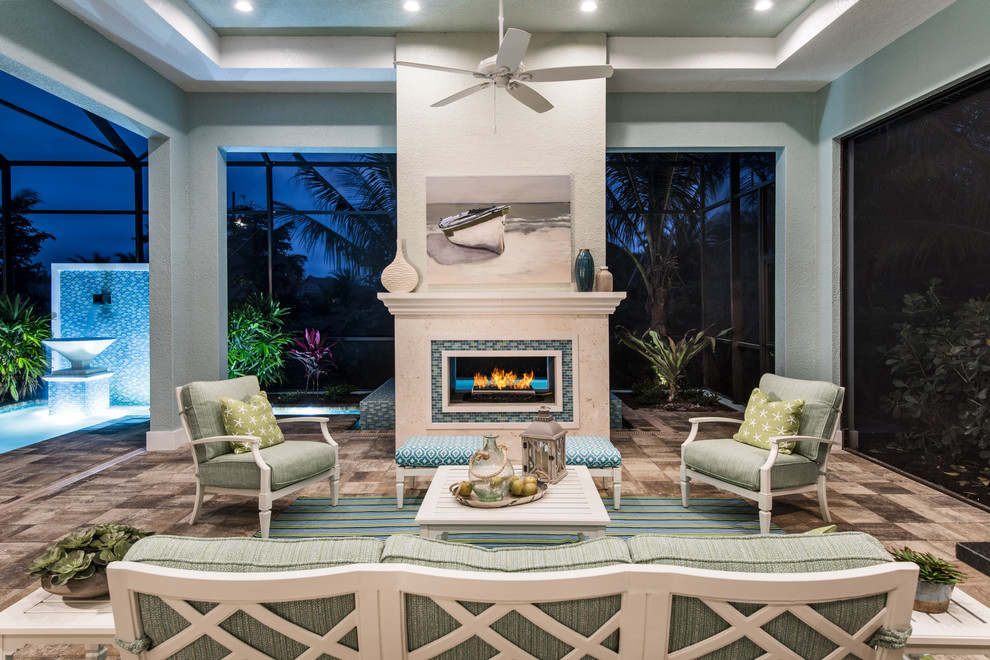 Beach style patio in Miami with tile, a roof extension and with fireplace.
