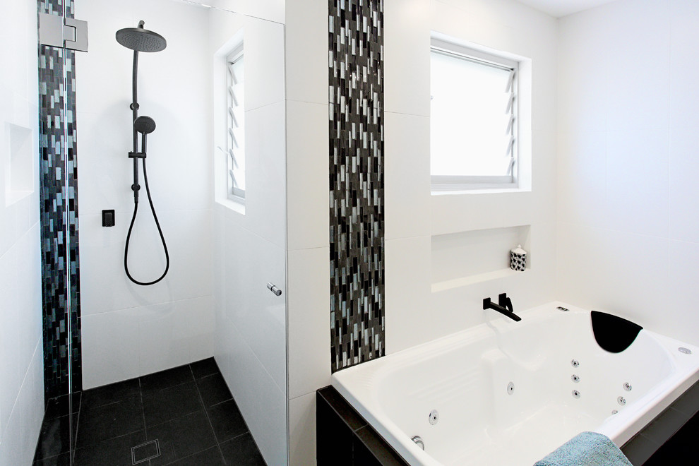 Mid-sized contemporary master bathroom in Sydney with flat-panel cabinets, dark wood cabinets, a hot tub, an alcove shower, black and white tile, porcelain tile, white walls, porcelain floors, an integrated sink and solid surface benchtops.