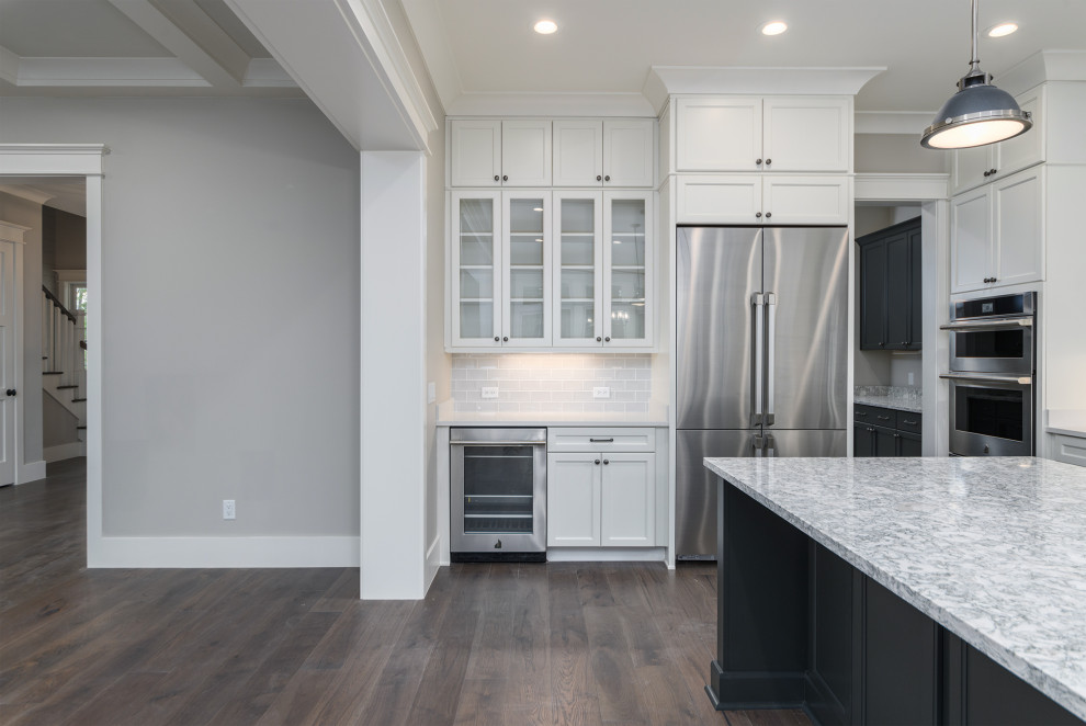 Kitchen - transitional brown floor kitchen idea with a farmhouse sink, gray backsplash, subway tile backsplash, stainless steel appliances, an island and white countertops