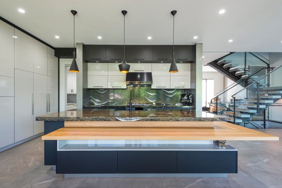Mid-sized contemporary l-shaped eat-in kitchen in Vancouver with a drop-in sink, flat-panel cabinets, white cabinets, quartz benchtops, black splashback, engineered quartz splashback, panelled appliances, cement tiles, with island, grey floor and black benchtop.