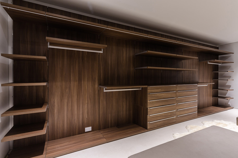 This is an example of a large contemporary gender-neutral walk-in wardrobe in Los Angeles with flat-panel cabinets, light wood cabinets, ceramic floors and beige floor.