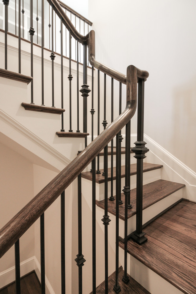 Imagen de escalera suspendida tradicional grande con escalones de madera, contrahuellas de madera pintada y barandilla de metal