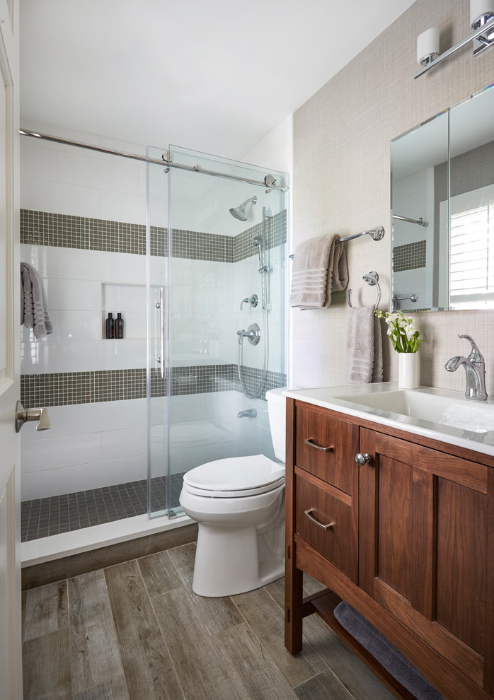 Inspiration for a small transitional 3/4 bathroom in Chicago with an alcove shower, a two-piece toilet, white tile, ceramic tile, beige walls, porcelain floors, an integrated sink, brown floor, a sliding shower screen, white benchtops, dark wood cabinets and shaker cabinets.