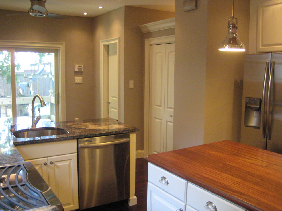 Example of a transitional l-shaped eat-in kitchen design in Philadelphia with a single-bowl sink, raised-panel cabinets, white cabinets, granite countertops, brown backsplash, stone tile backsplash and stainless steel appliances