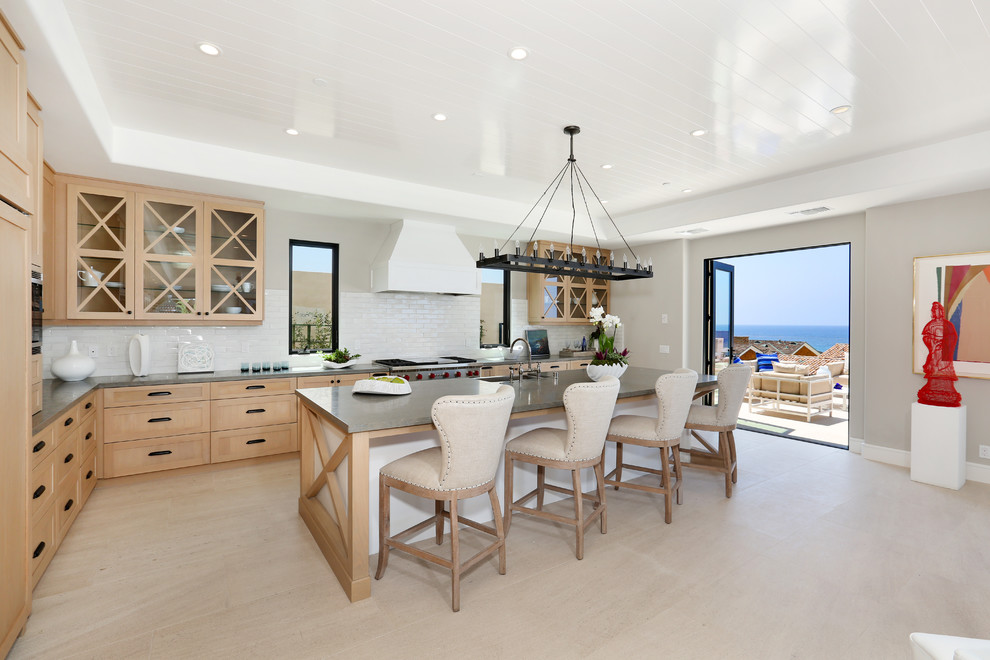 Photo of a mid-sized beach style l-shaped kitchen in Orange County with light wood cabinets, panelled appliances, with island, a farmhouse sink, shaker cabinets, white splashback and subway tile splashback.