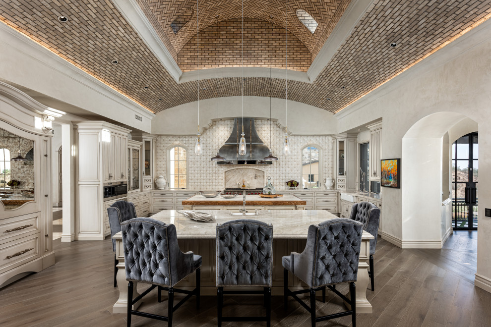 Example of an u-shaped eat-in kitchen design in Phoenix with raised-panel cabinets and two islands