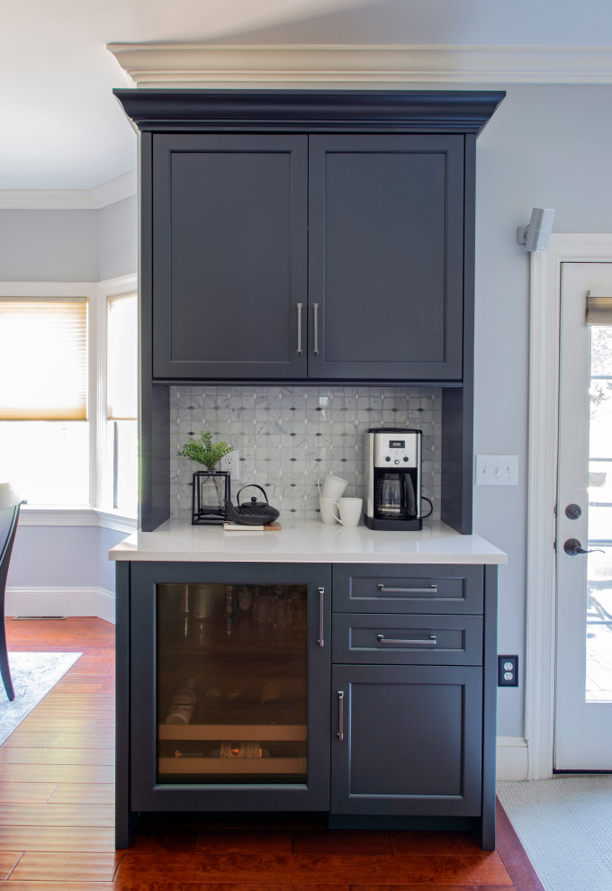 Transitional medium tone wood floor kitchen photo with an undermount sink, shaker cabinets, quartz countertops, gray backsplash, porcelain backsplash, stainless steel appliances, an island and white countertops