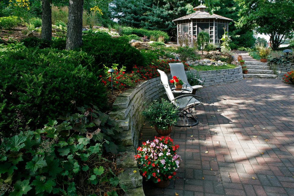 This is an example of a large traditional courtyard patio in Other with brick pavers and a gazebo/cabana.