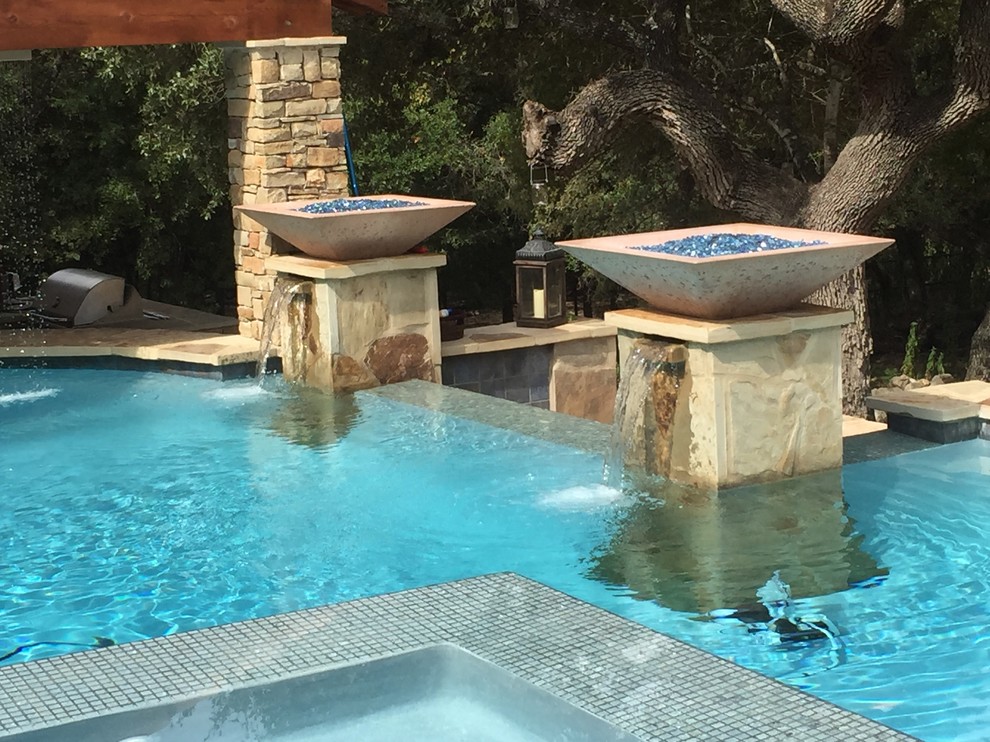 Large mountain style backyard custom-shaped infinity hot tub photo in Austin with decking