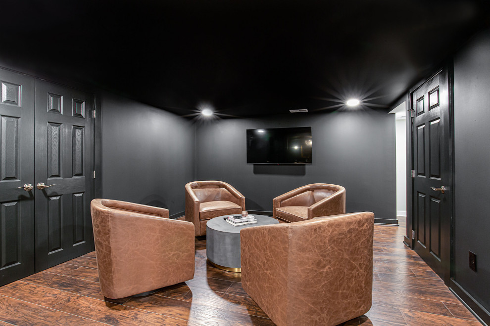 На фото: большой домашний кинотеатр в современном стиле с черными стенами, полом из винила и коричневым полом