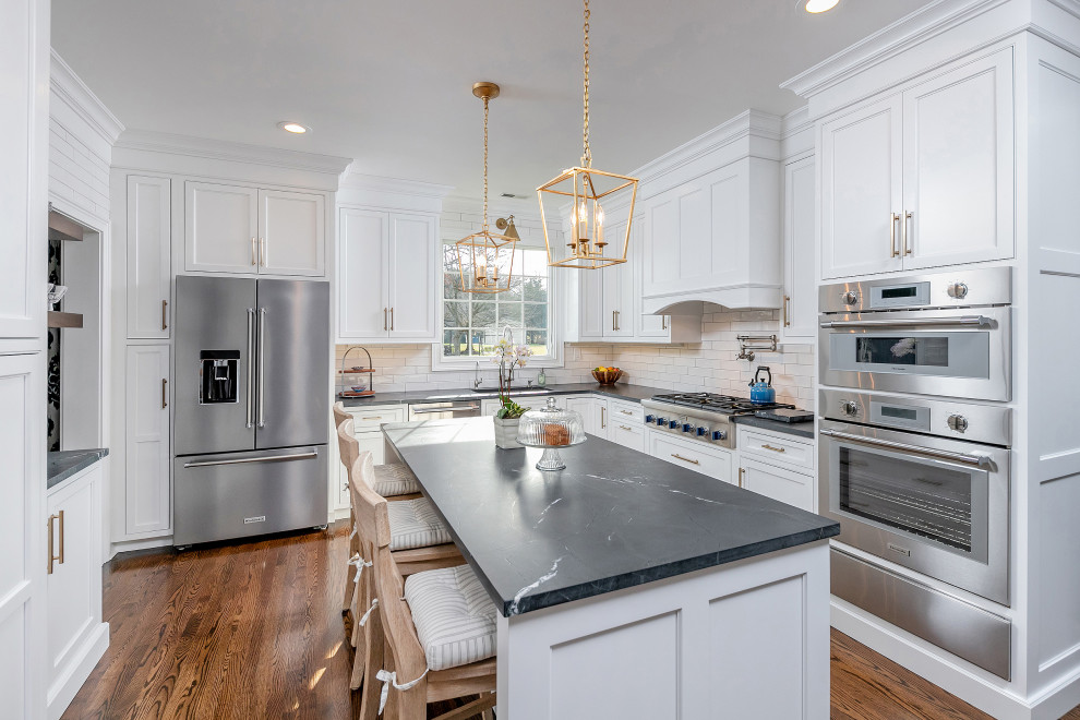 Traditional eat-in kitchen in Philadelphia with an undermount sink, beaded inset cabinets, white cabinets, quartzite benchtops, white splashback, subway tile splashback, stainless steel appliances, cork floors, with island and black benchtop.