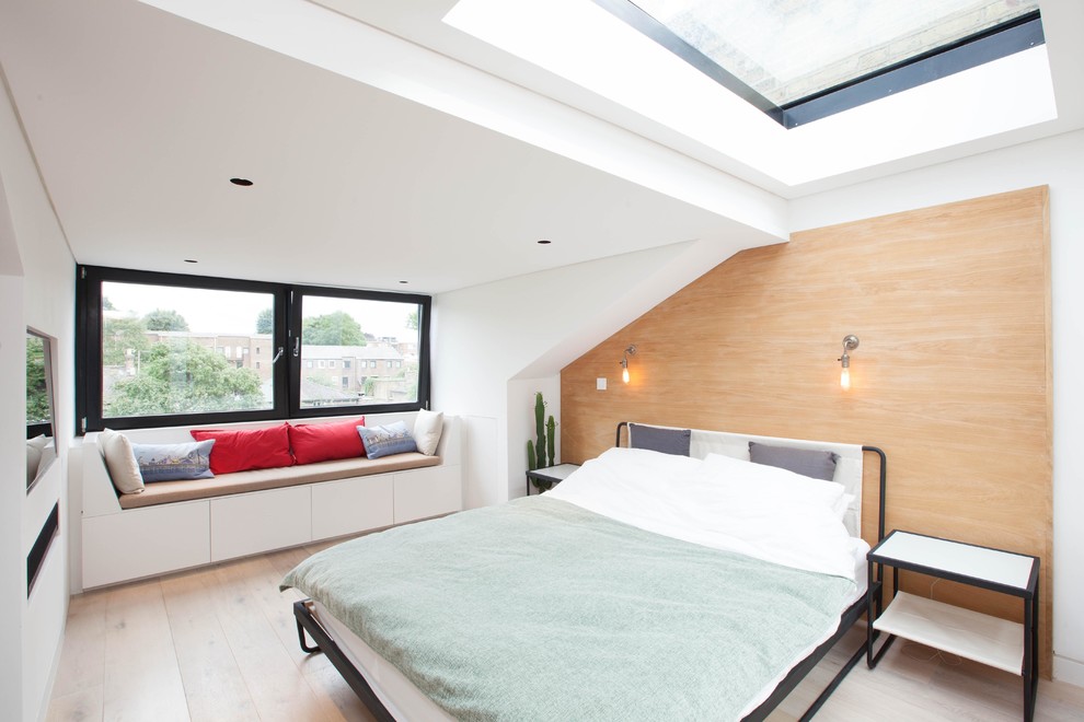 Contemporary master bedroom in London with white walls and light hardwood floors.