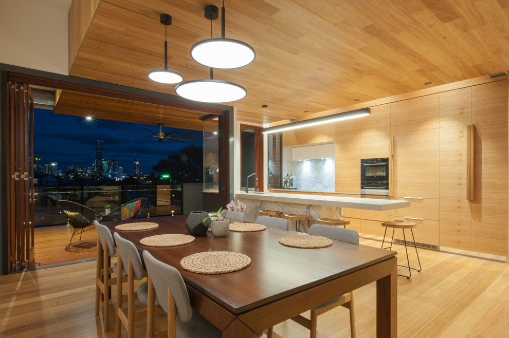 This is an example of a mid-sized contemporary open plan dining in Brisbane with light hardwood floors.