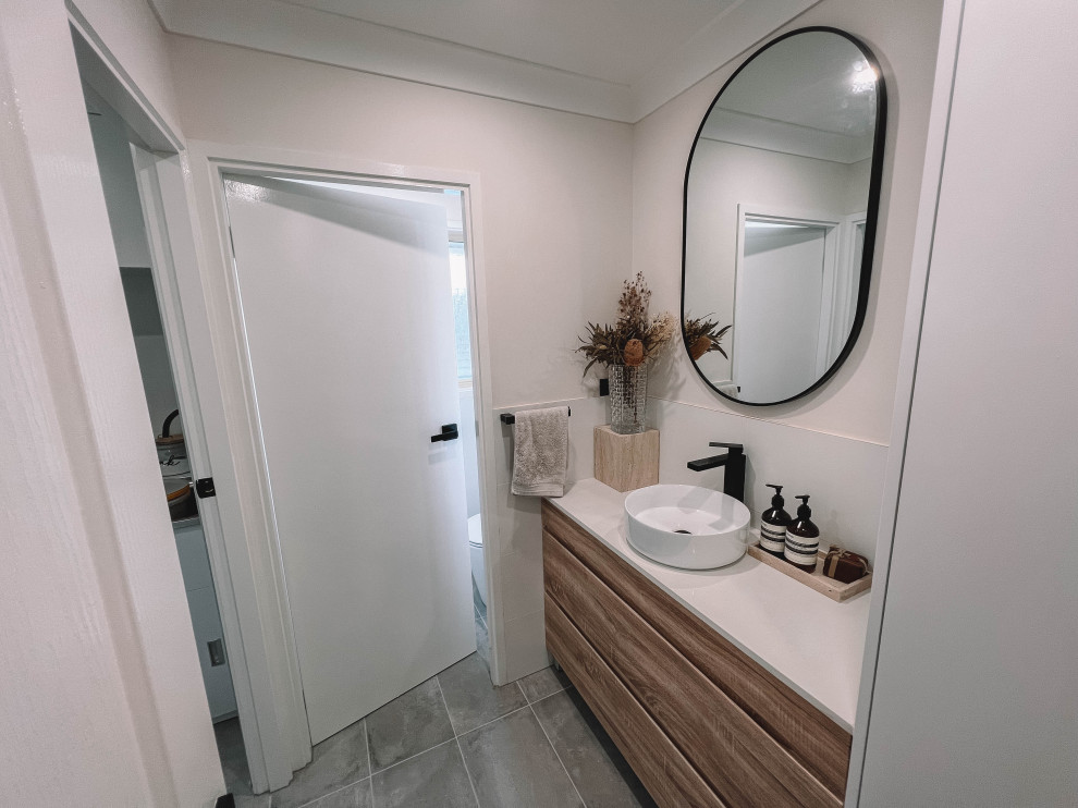 Design ideas for a medium sized scandinavian cloakroom in Newcastle - Maitland with flat-panel cabinets, light wood cabinets, a one-piece toilet, white tiles, ceramic tiles, white walls, ceramic flooring, a vessel sink, engineered stone worktops, grey floors, white worktops, a freestanding vanity unit, a wood ceiling and wood walls.