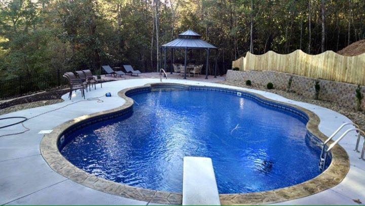 Large tropical backyard custom-shaped natural pool in Atlanta with stamped concrete.