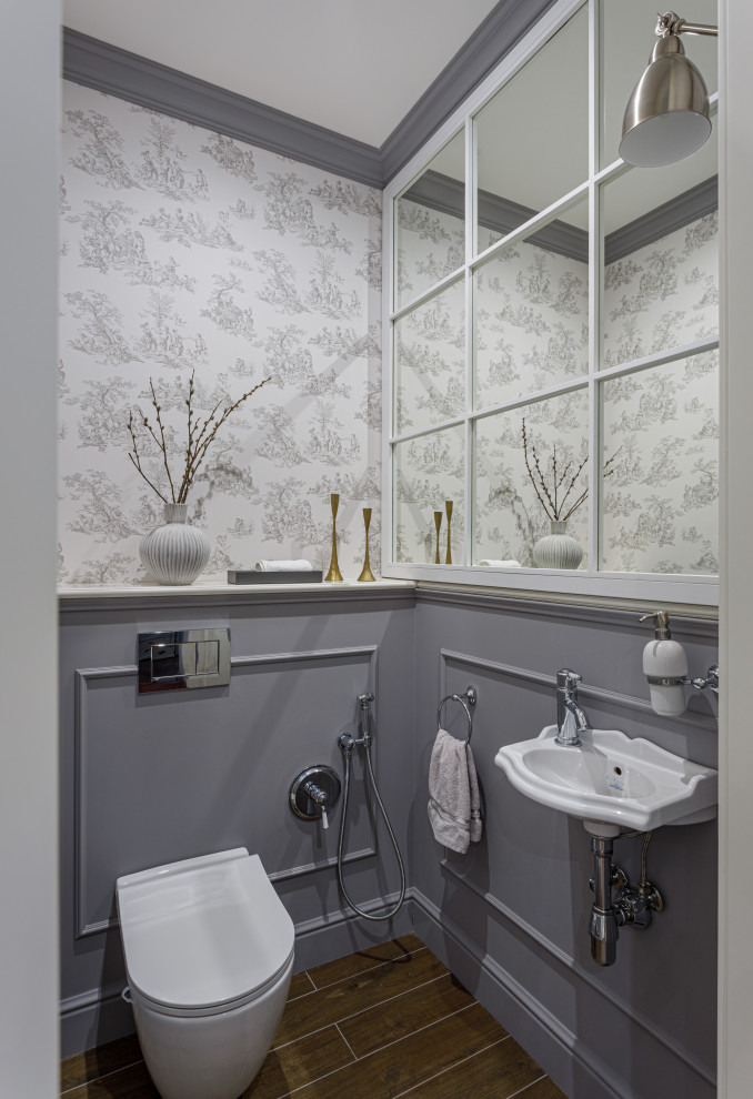 Foto på ett mellanstort funkis toalett, med en vägghängd toalettstol, porslinskakel, grå väggar, klinkergolv i porslin, ett väggmonterat handfat, brunt golv och grå kakel