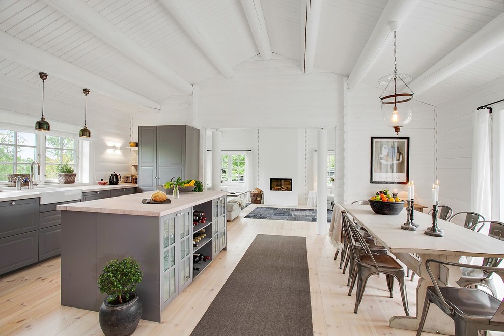 Inspiration for a large country single-wall open plan kitchen in Other with a farmhouse sink, raised-panel cabinets, grey cabinets, light hardwood floors, with island and wood benchtops.