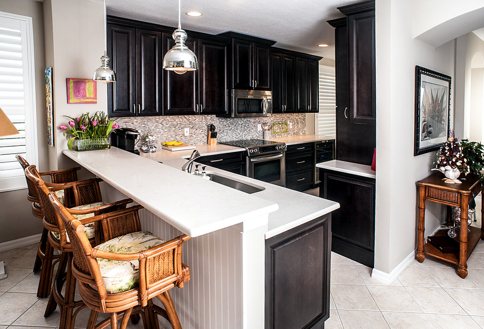 Inspiration for a mid-sized transitional l-shaped eat-in kitchen in Tampa with raised-panel cabinets, dark wood cabinets, quartzite benchtops, mosaic tile splashback, stainless steel appliances, a peninsula, an undermount sink, multi-coloured splashback, porcelain floors and white floor.