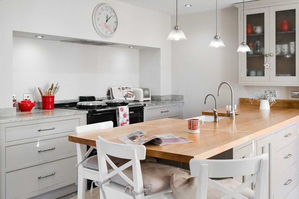 Mid-sized contemporary eat-in kitchen in Cambridgeshire with grey cabinets, black appliances and with island.