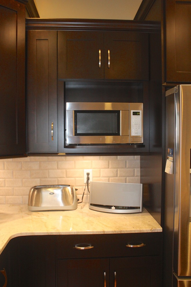 Eat-in kitchen - mid-sized contemporary u-shaped medium tone wood floor eat-in kitchen idea with shaker cabinets, dark wood cabinets, white backsplash, stainless steel appliances, an island, a double-bowl sink and subway tile backsplash