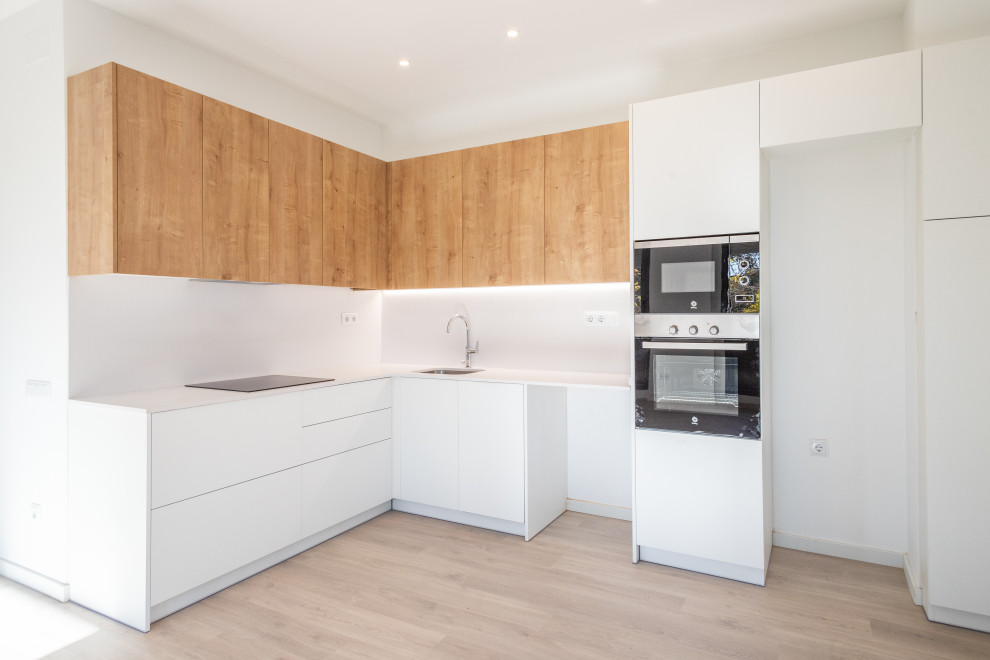 Idéer för att renovera ett mellanstort funkis vit vitt kök, med en enkel diskho, släta luckor, vita skåp, vitt stänkskydd, rostfria vitvaror, mellanmörkt trägolv och brunt golv