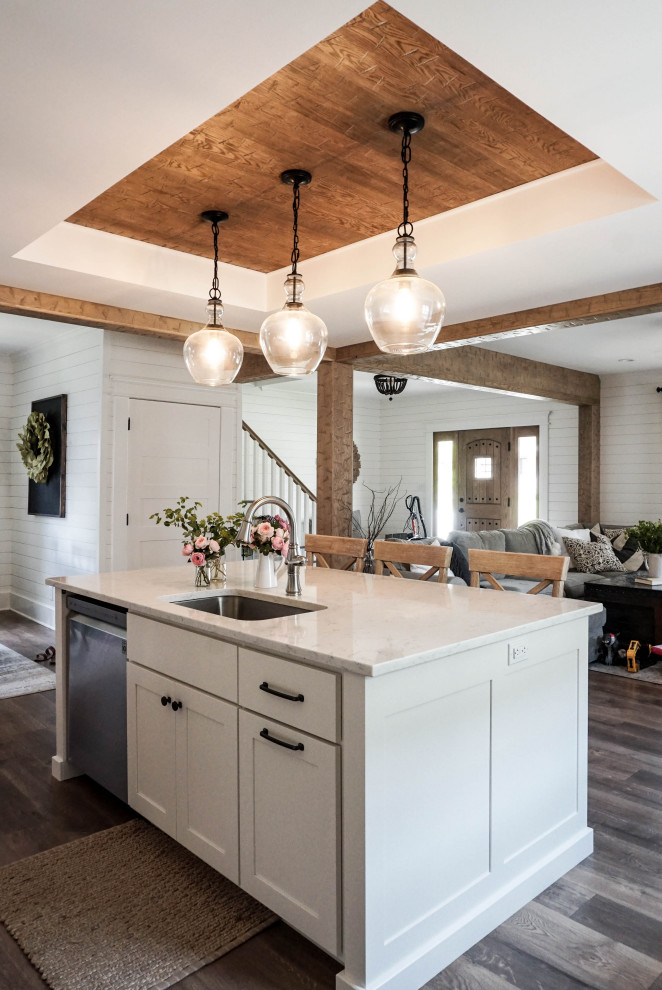 This is an example of a mid-sized country l-shaped eat-in kitchen in Other with an undermount sink, shaker cabinets, white cabinets, quartz benchtops, grey splashback, marble splashback, stainless steel appliances, medium hardwood floors, with island, brown floor, white benchtop and recessed.