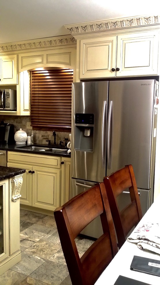 Example of a mid-sized classic l-shaped eat-in kitchen design with a double-bowl sink, raised-panel cabinets, beige cabinets, granite countertops, gray backsplash, stone tile backsplash, black appliances and an island