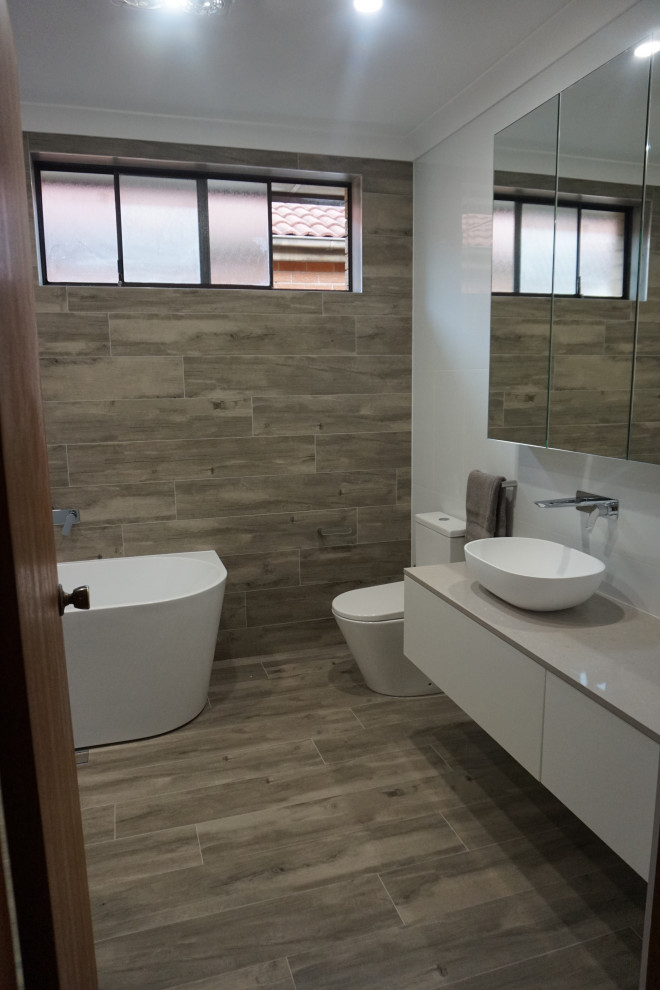 Inspiration for a mid-sized modern master bathroom in Sydney with white cabinets, a freestanding tub, an open shower, a two-piece toilet, white tile, ceramic tile, white walls, ceramic floors, a drop-in sink, engineered quartz benchtops, grey floor, an open shower, grey benchtops, a single vanity and a floating vanity.
