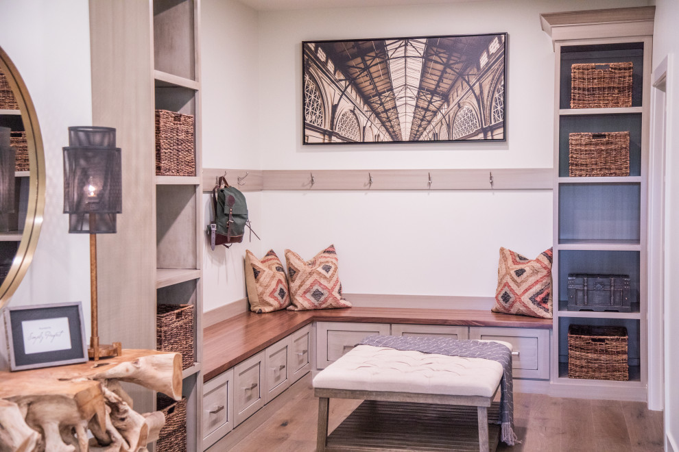 Mid-sized transitional medium tone wood floor and brown floor mudroom photo with white walls and a medium wood front door