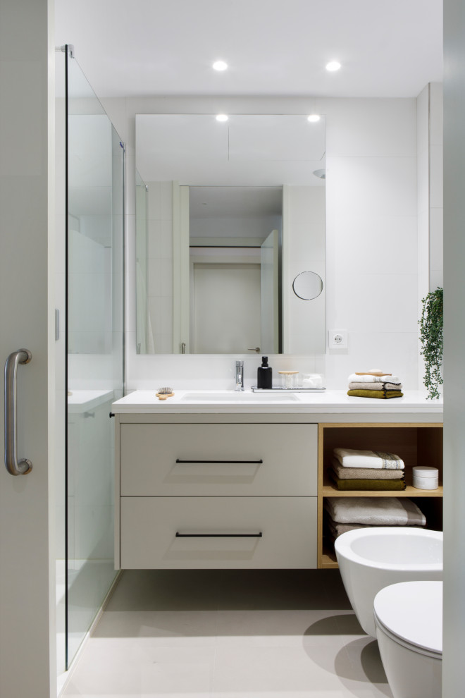 This is an example of a classic ensuite bathroom in Barcelona with grey cabinets, a two-piece toilet, white tiles, white walls, a submerged sink, white floors, white worktops, a single sink and a built in vanity unit.