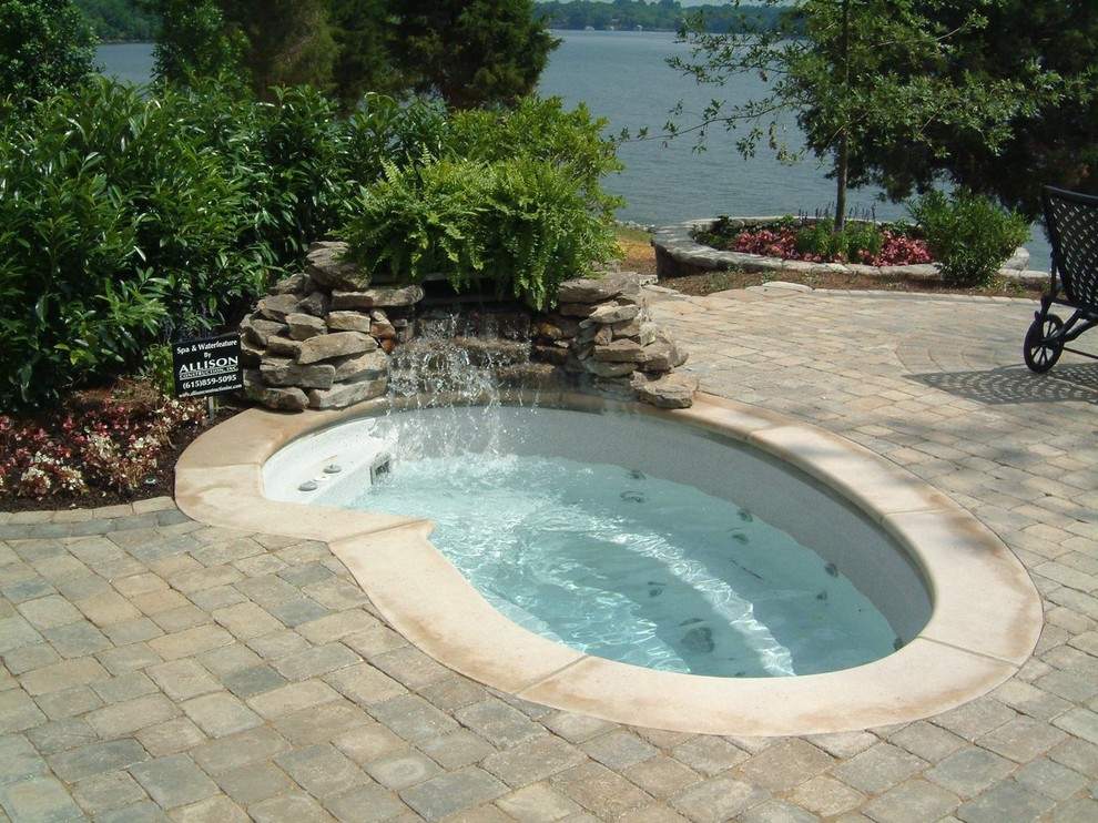 Mid-sized tropical backyard kidney-shaped pool in Nashville with a hot tub and brick pavers.