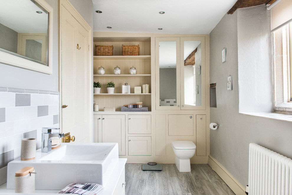 This is an example of a mid-sized transitional master bathroom in Other with a vessel sink, shaker cabinets, beige cabinets, solid surface benchtops, a drop-in tub, an alcove shower, a one-piece toilet and ceramic tile.