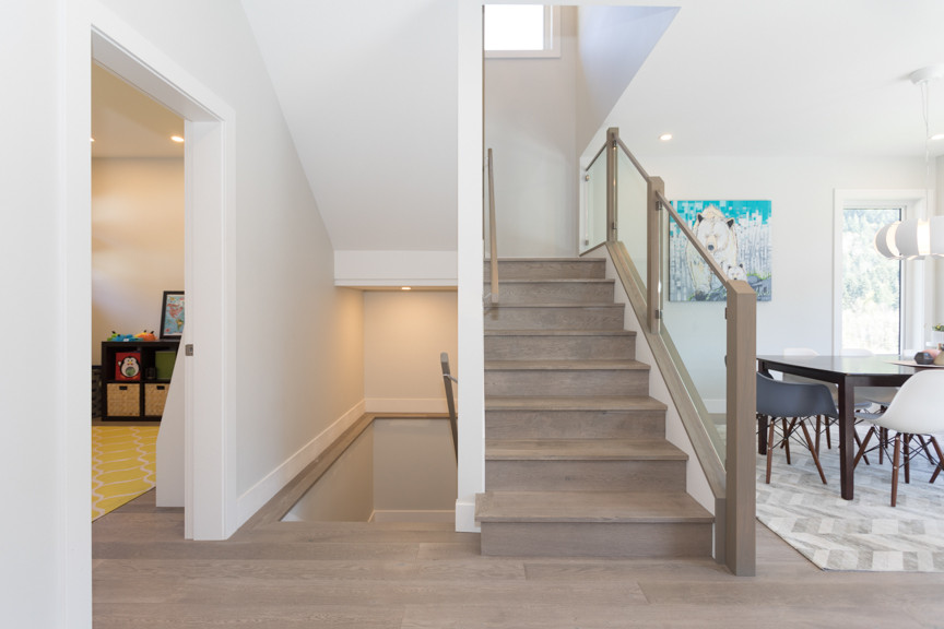 This is an example of a contemporary wood u-shaped glass railing staircase in Vancouver with wood risers.