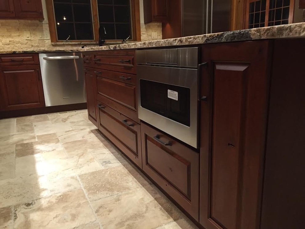 Inspiration for a large arts and crafts l-shaped separate kitchen in Denver with an undermount sink, raised-panel cabinets, dark wood cabinets, granite benchtops, beige splashback, stone tile splashback, stainless steel appliances, travertine floors, with island and beige floor.