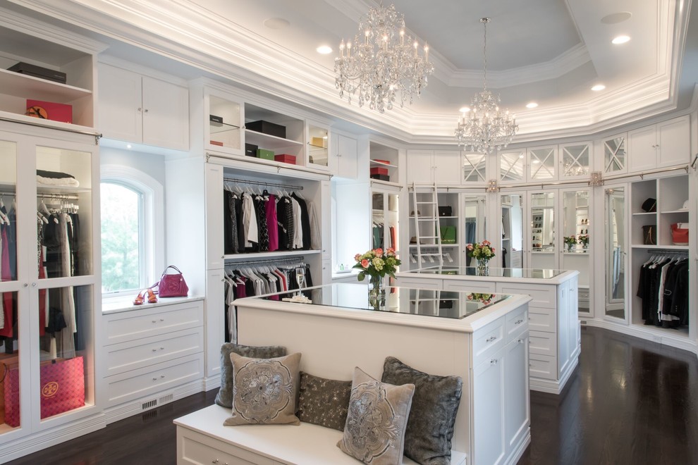 Large traditional women's walk-in wardrobe in St Louis with raised-panel cabinets, white cabinets and dark hardwood floors.