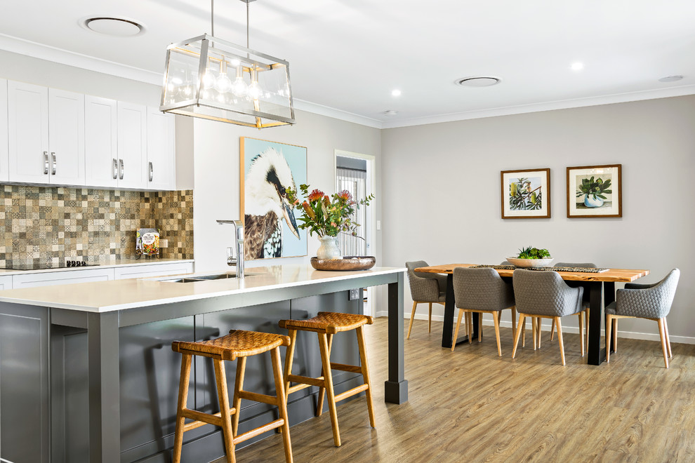 Modern eat-in kitchen in Other with a double-bowl sink, shaker cabinets, white cabinets, beige splashback, medium hardwood floors, with island, brown floor and white benchtop.