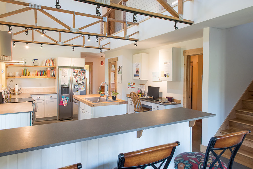 Inspiration for a mid-sized transitional l-shaped concrete floor and gray floor open concept kitchen remodel with a drop-in sink, shaker cabinets, white cabinets, wood countertops, yellow backsplash, stainless steel appliances, an island and brown countertops