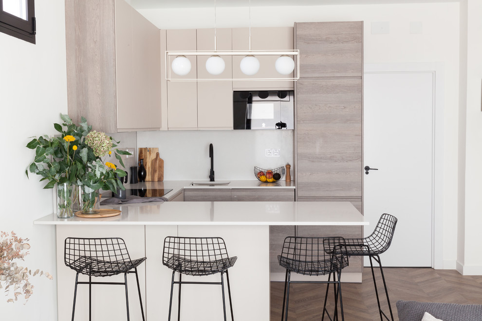 Design ideas for a mid-sized scandinavian u-shaped open plan kitchen in Madrid with an undermount sink, flat-panel cabinets, beige cabinets, quartz benchtops, laminate floors, a peninsula, brown floor, white splashback and white benchtop.