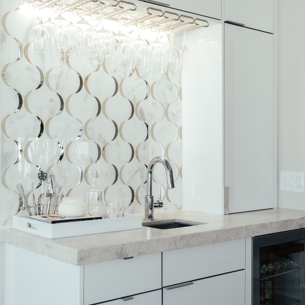 Inspiration for a large contemporary single-wall wet bar in Orange County with an undermount sink, flat-panel cabinets, white cabinets, quartzite benchtops, white splashback, mosaic tile splashback, beige benchtop, brown floor and medium hardwood floors.