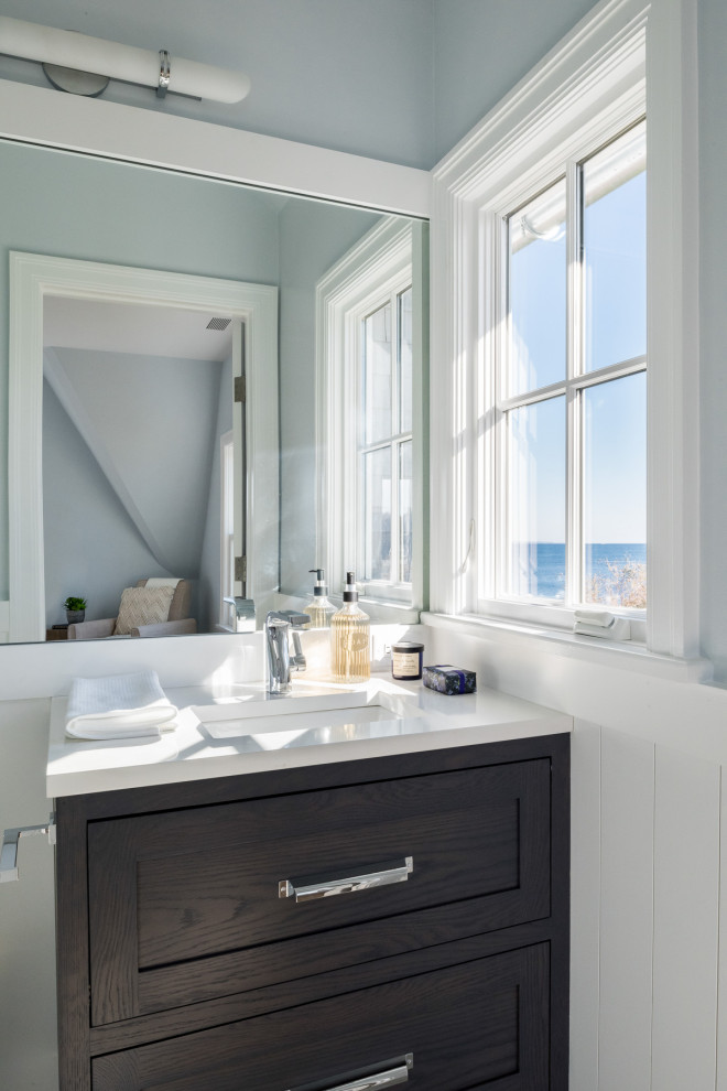 Small beach style kids bathroom in New York with recessed-panel cabinets, blue cabinets, an alcove shower, a two-piece toilet, white tile, subway tile, blue walls, porcelain floors, an undermount sink, solid surface benchtops, grey floor, a hinged shower door and white benchtops.