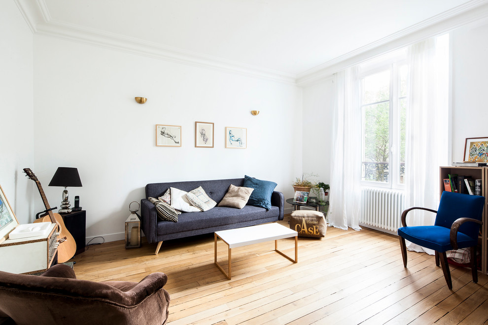 Photo of a scandinavian open concept family room in Paris with white walls and light hardwood floors.
