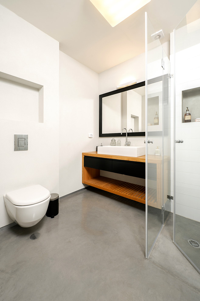 Photo of a contemporary bathroom in Tel Aviv with a vessel sink, a wall-mount toilet and concrete floors.
