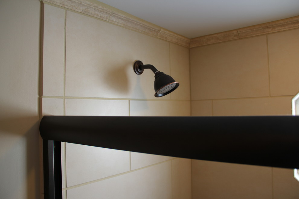 Tub/shower combo - transitional brown tile and porcelain tile porcelain tile tub/shower combo idea in Columbus with a vessel sink, an undermount tub, a two-piece toilet, raised-panel cabinets, medium tone wood cabinets, granite countertops and beige walls