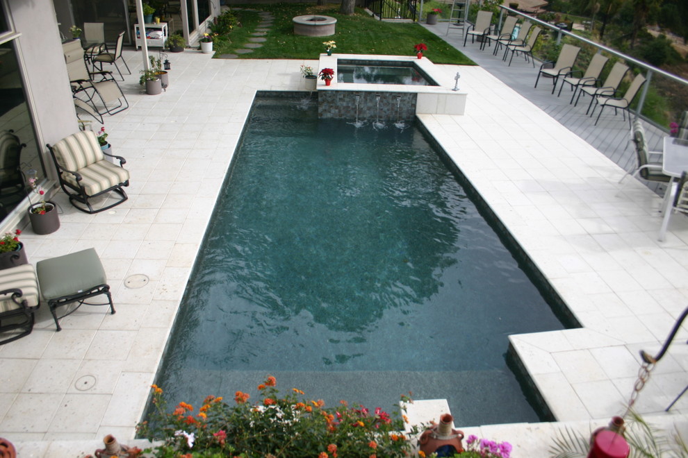 Photo of a small modern backyard rectangular lap pool in Los Angeles with a water feature and concrete pavers.