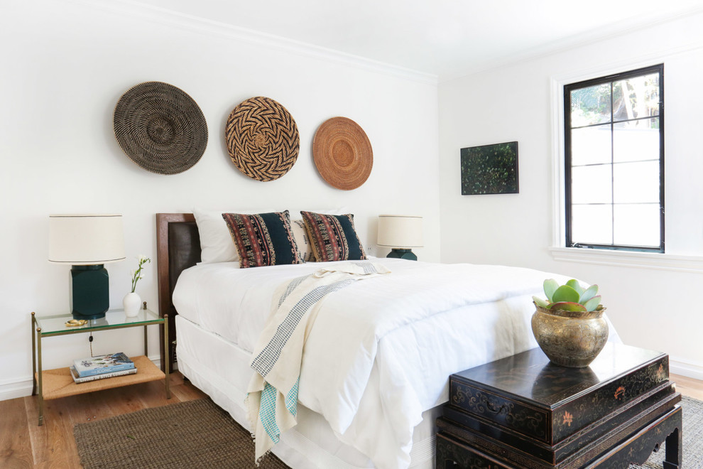 Inspiration for a mid-sized eclectic guest bedroom in Los Angeles with white walls, light hardwood floors and no fireplace.