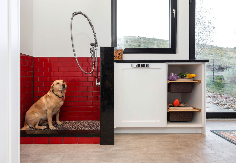 Inspiration for a large contemporary utility room in Denver with flat-panel cabinets, white cabinets, granite benchtops, red splashback, ceramic splashback, white walls, beige floor and black benchtop.