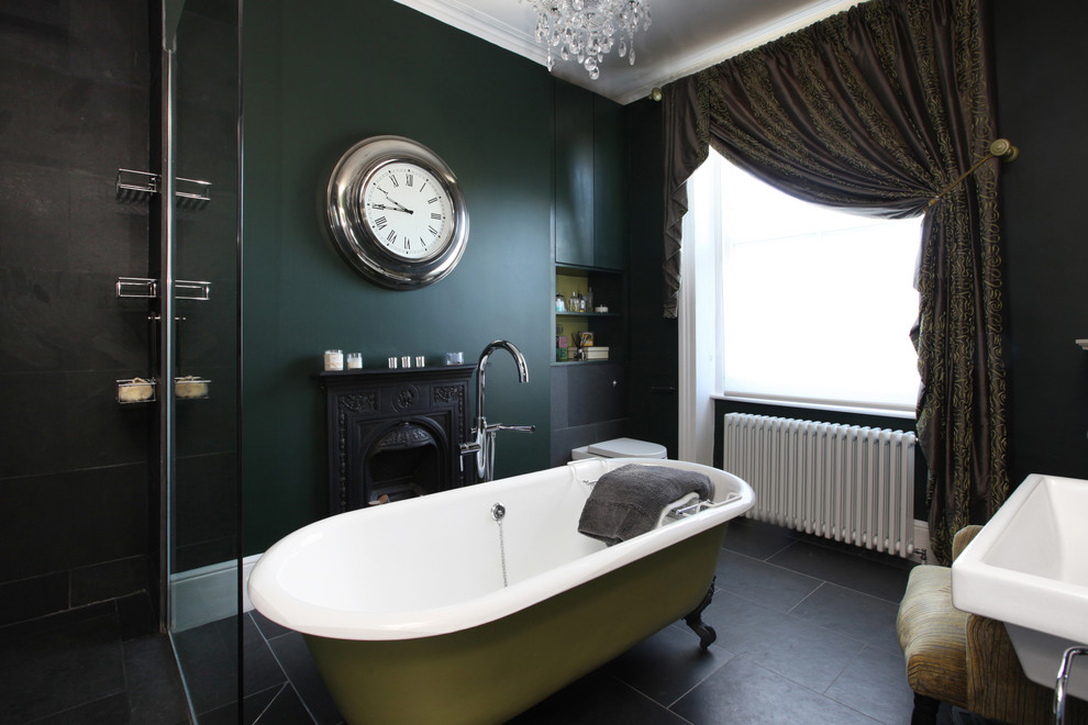 This is an example of a transitional bathroom in London with a claw-foot tub, green walls and a pedestal sink.